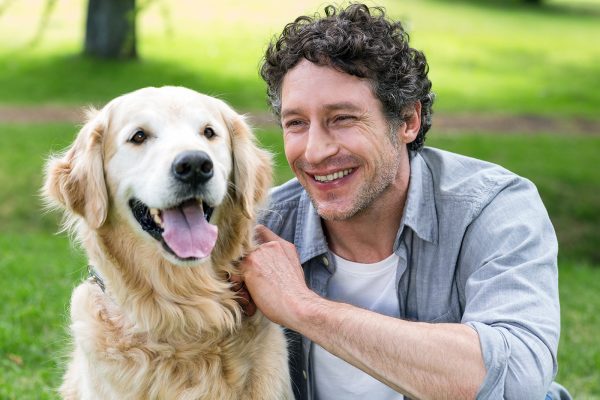 smiling-man-with-his-dog-in-park-on-a-sunny-day-PDNWL2X